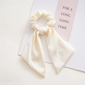 Detailed view of elegant cream satin scrunchie with long ribbons and silky texture