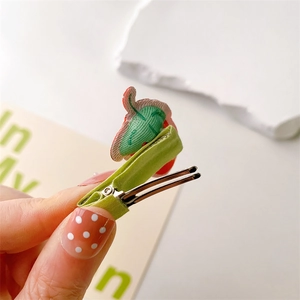 Detailed close-up of a cute embroidered green cloth-wrapped hair clip for toddlers