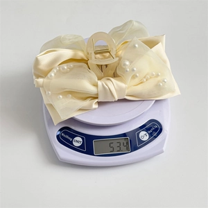 Weight measurement of cream ribbon hair claw with pearls on electronic scale, 53.4g