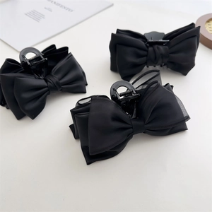 Detailed view of three black double-sided bow hair claws with matte satin and mesh texture