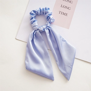 Close-up of light blue satin scrunchie with long ribbon bow showing silky fabric texture