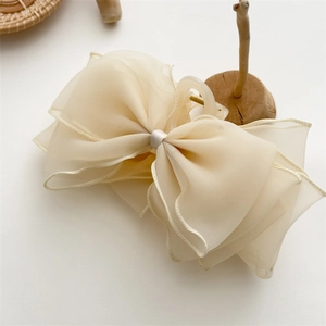 Détail de la pince à cheveux avec nœud en tulle champagne sur support en bois