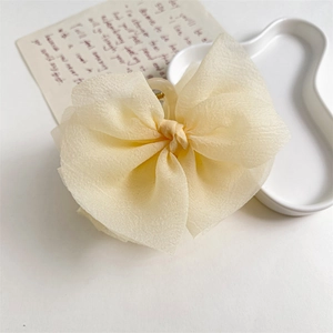 Dettaglio di un grande fermaglio per capelli con fiocco in chiffon color crema