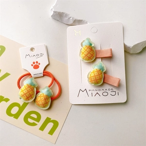 Detail of cute embroidered pineapple hair ties and clips on a branded display card