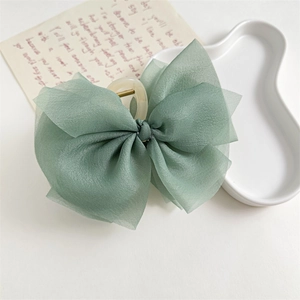 Dettaglio di un grande fermaglio per capelli in chiffon verde con fiocco elegante