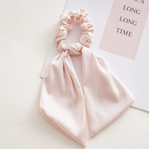 Detail view of smooth light pink satin scrunchie with elegant long flowing streamers