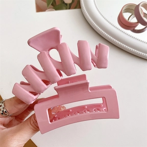 Dettaglio di fermagli per capelli in resina rosa crema con design ondulati e rettangolari