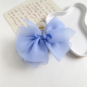Dettaglio di un grande fermaglio per capelli a fiocco in chiffon azzurro su vassoio