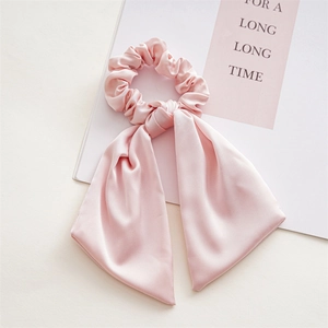 Detail of light pink satin scrunchie with long ribbon tails and smooth texture
