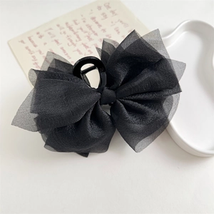 Dettaglio di una molletta per capelli con fiocco in chiffon nero e rete trasparente chic