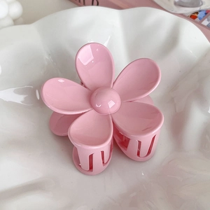 Dettaglio di una pinza per capelli a fiore in resina rosa crema lucida su base in ceramica