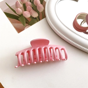 Dettaglio di una molletta per capelli in resina rosa crema lucida per donne su bianco
