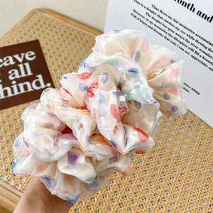 Dettaglio di scrunchie in rete color crema con pois colorati e volant a strati
