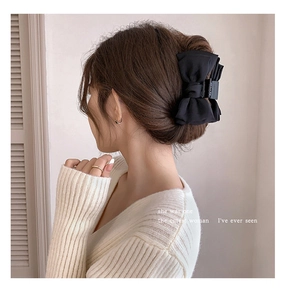 Close-up of a large black double-layered bow hair claw clip styled on a woman hair bun