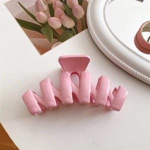 Dettaglio di una pinza per capelli in resina rosa crema lucida con denti a onda