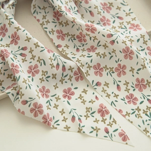 Close-up of floral hair scrunchie fabric showing pink flowers on cream chiffon material