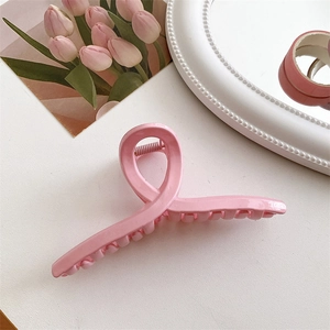 Macro della molletta per capelli in resina rosa crema lucida con design a croce curva