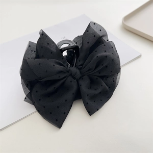 Close-up of a large black double-layered bow hair claw with elegant polka dot mesh texture