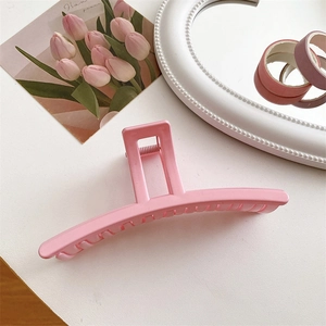 Dettaglio di un fermaglio per capelli in resina rosa crema su una scrivania bianca
