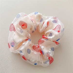 Dettaglio di un elastico in mesh a doppio strato con pois rossi e blu su chiffon crema