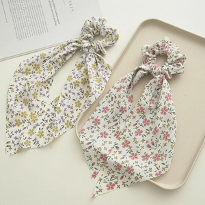 Detailed close-up of floral print scrunchies with long ribbons in yellow and pink hues