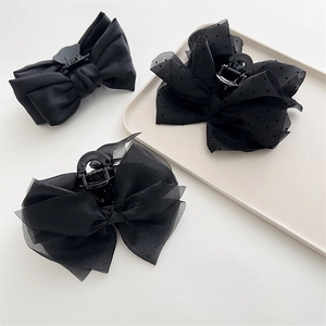 Three-piece black bow hair claw set in satin and organza on a minimalist display tray