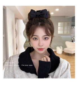 Detail view of a large black fabric bow hair claw clip worn on a woman's hair