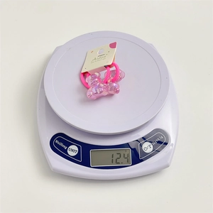 Macro detail of cute pink jelly bear hair ties on a digital scale for weight display