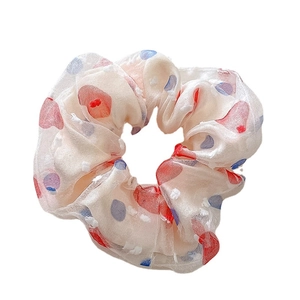 Scrunchie in organza a pois colorati con morbida floccatura su sfondo bianco puro