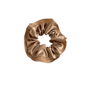Champagne gold satin scrunchie with ruffled edges and metallic luster for high-elastic hair styling