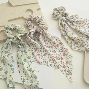 Three floral pattern scrunchies with long ribbons in green, pink, and purple chiffon fabric