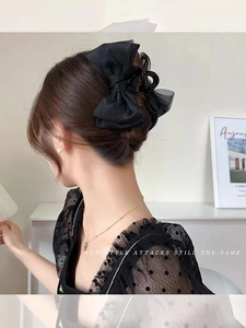 Rear view of model wearing large black double-layered silk bow claw hair clip