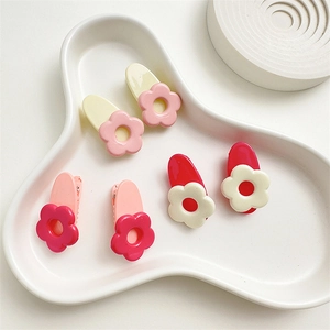Set di sei fermagli per capelli a fiore in colori pastello su un vassoio di ceramica