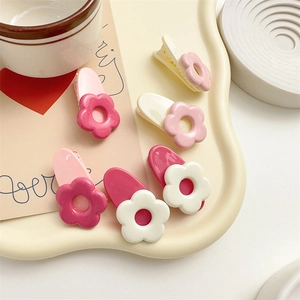 Dettaglio di sei mollette a fiore crema e rosa su un vassoio decorativo bianco