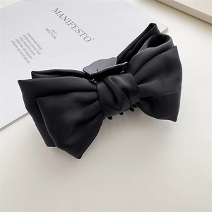 Detail of a large black satin double-layer bow hair claw clip with a glossy finish