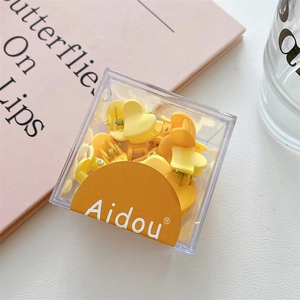 Mini pinces à cheveux coeur mat dans des tons jaunes rangées dans une boîte transparente