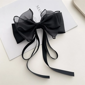 Macro detail of large black double-layered bow hair claw with satin and organza ribbons
