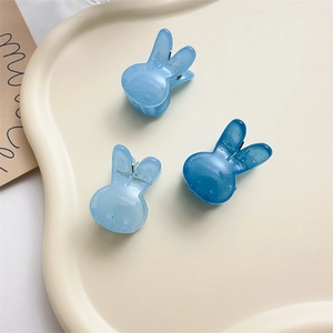 Vue détaillée de trois mini pinces à cheveux lapin bleu transparent avec paillettes sur plat