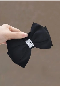 Macro shot of a large black satin double bow hair claw clip with four rows of pearls
