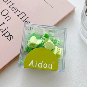 Détail de mini pinces à cheveux en forme de cœur dégradé vert dans une boîte transparente