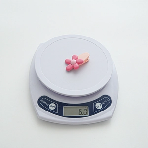Detail showing a pink flower hair clip weighing 6.0g on a white electronic scale