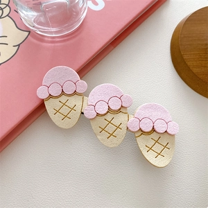 Close-up of cute cartoon ice cream cone hair clip with three pink and yellow felt treats