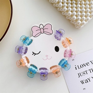 Macro detail of colorful glitter resin mini hair claws on a cute rabbit display card