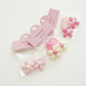 Detailed view of pink and cream floral hair clips in elegant retail packaging