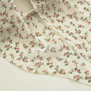 Detail of floral chiffon scrunchie with crinkled texture and pink flower pattern