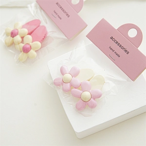 Detail view of pink and white resin flower hair clips in premium handmade packaging