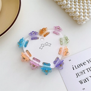 Detail of colorful glittery star-shaped mini hair claws on a heart-shaped card