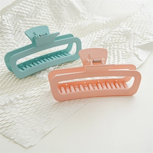 Macro shot of large 13cm matte shark hair clips in blue and pink on white texture