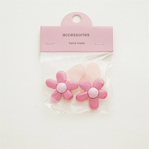 Detailed top view of two pink flower hair clips on a white background with packaging card