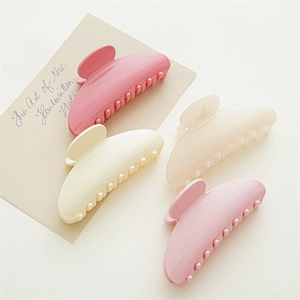 Detailed view of four large resin hair claws in pink and cream tones for thick hair
